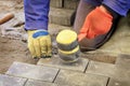 Paving the tiles on the sidewalk, the worker lay the tile, aligning it on the thread