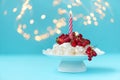 Pavlova birthday fruit cake with burn candle on pastel blue background against blurred lights. Selective focus. Healthy food or