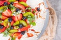 Pavlova cake with cream and fresh summer berries and kiwi on wooden background. Close up of Pavlova dessert with forest fruit and Royalty Free Stock Photo