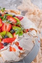 Pavlova cake with cream and fresh summer berries and kiwi on wooden background. Close up of Pavlova dessert with forest fruit and Royalty Free Stock Photo