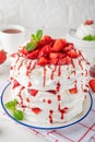 Pavlova layered cake with fresh strawberries, sauce and whipped cream on a white wooden background. Summer beautiful cake. Royalty Free Stock Photo