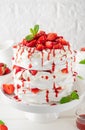 Pavlova layered cake with fresh strawberries, sauce and whipped cream on a white wooden background. Summer beautiful cake. Royalty Free Stock Photo