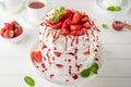 Pavlova layered cake with fresh strawberries, sauce and whipped cream on a white wooden background. Summer beautiful cake. Royalty Free Stock Photo