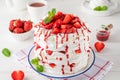 Pavlova layered cake with fresh strawberries, sauce and whipped cream on a white wooden background. Summer beautiful cake. Royalty Free Stock Photo