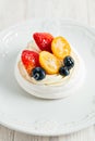 Pavlova`s meringue cake with cream and glazed fruit on white plate on wooden table Royalty Free Stock Photo