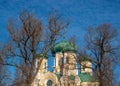 Pavlovsky Cathedral on a sunny spring day. Fragment. Rooks on the trees. The blue sky, green domes and the yellow walls