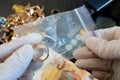 Pawnshop worker packing a gold wedding ring on many golden and silver jewelleries and jewelry scales background, top view