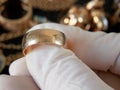 Pawnshop worker verify golden wedding ring on many golden and silver jewelleries and money background. Customers Buy and Sell