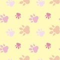 Paws pattern. Silhouettes of paws, cat s feet, dog s footprint. Pastel pink, nude on a yellow background. Seamless Royalty Free Stock Photo