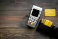 Pay by bank card, pay by credit card. Payment terminal near card and wallet with bank and credit cards on dark wooden