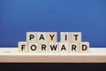 Pay It Forward alphabet letter on blue and wooden shelves background Royalty Free Stock Photo