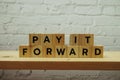 Pay It Forward alphabet letter on white brick wall and wooden shelves background Royalty Free Stock Photo