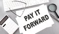 PAY IT FORWARD text on paper with keyboard, calculator on grey background Royalty Free Stock Photo