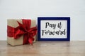 Pay it forward typography text and gift box on wooden table and white wall background Royalty Free Stock Photo