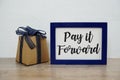 Pay it forward typography text and gift box on wooden table and white wall background Royalty Free Stock Photo