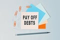 Pay off debts - text on sticky note paper on gray background. Closeup of a personal agenda. Top view Royalty Free Stock Photo