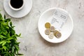 Pay restaurant bill by cash. Reciept and coins on plate on grey background top view