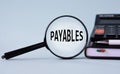 PAYABLES - words on magnifying glass on a light background with calculator, notepad and pen Royalty Free Stock Photo