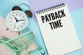 Payback Time text written on notepad with alarm clock and trolley shopping cart Royalty Free Stock Photo