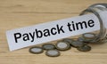 PAYBACK TIME words on a white strip of paper with a can of money Royalty Free Stock Photo