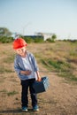 Payday concept of happy laughing small kid in orange helmet with tool box walking from work place at factory plant Royalty Free Stock Photo