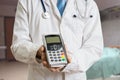 Paying for private healthcare. Doctor holds payment terminal in hands