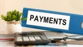 Payment - blue binder on desk in the office with calculator, pen and green potted plant, concept Royalty Free Stock Photo