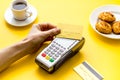 Payment by credit card. Hand hold card near terminal on yellow table