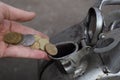Payment for the gas, fuel, gasoline, diesel concept. Hand dropping money, coin in the can of fuel
