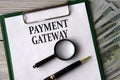 PAYMENT GATEWAY - words on a white sheet on the background of banknotes, magnifying glass and pen