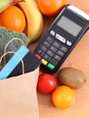 Payment terminal, contactless credit card, paper shopping bag and fruits with vegetables Royalty Free Stock Photo