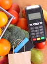 Payment terminal, contactless credit card, paper shopping bag and fruits with vegetables Royalty Free Stock Photo