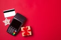 Payment terminal with credit card and gift on a red paper background. Christmas sale concept Royalty Free Stock Photo