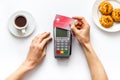 Payment transactions. Hand hold card near terminal on white cafe table top-down