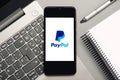 Paypal logo on black screen of smartphone with laptop and notebook Royalty Free Stock Photo