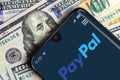Paypal logo on smartphone screen and dollar bills Royalty Free Stock Photo