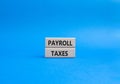 Payroll taxes symbol. Concept word Payroll taxes on wooden blocks. Beautiful blue background. Businessman hand. Business and