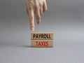 Payroll taxes symbol. Concept word Payroll taxes on wooden blocks. Beautiful grey background. Businessman hand. Business and