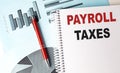 PAYROLL TAXES text on a notebook with pen on a chart background