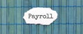 PAYROLL text on the piece of paper on the green wood background