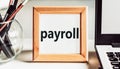 PAYROLL text in wooden frame on office table