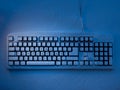PC keyboard covered with snow illuminated by blue neon light with inscription merry christmas Royalty Free Stock Photo