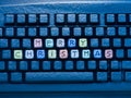 Computer keyboard with multicolored text merry christmas on buttons covered with snow illuminated by blue neon light Royalty Free Stock Photo