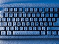 Computer keyboard with text merry christmas on buttons covered with snow lit by blue light Royalty Free Stock Photo