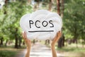 PCOS - Polycystic ovary syndrome, woman sickness lettering on white background in womans hands