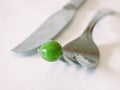 Pea on end of fork with knife Royalty Free Stock Photo
