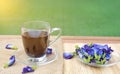 Pea flowers healthy drink on wood plank table against green grass field with rays of sunlight Royalty Free Stock Photo