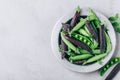 Pea. Greean and purple peas pods bowl on gray stone background, top view Royalty Free Stock Photo