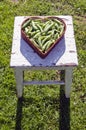 Pea pods in heart form basket on old seat Royalty Free Stock Photo