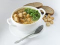 Pea soup in a white cup with greens and croutons.